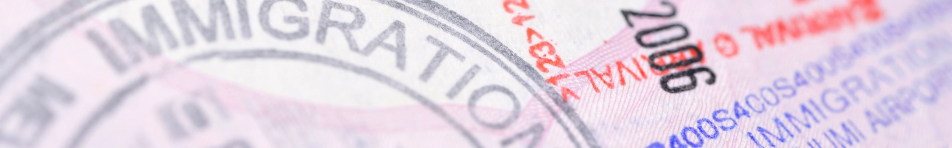 Close-up of passport pages with immigration entry stamps in red and blue ink.